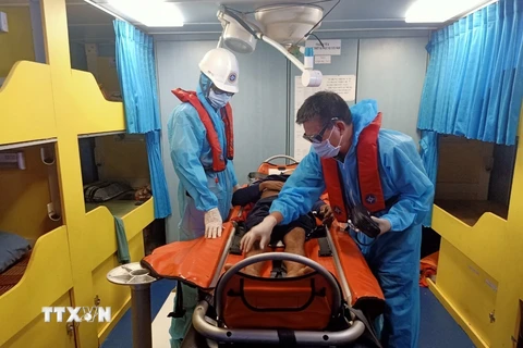 Nhân viên y tế trên tàu cứu nạn chuyên dụng SAR 413 tiến hành sơ cứu ban đầu cho thuyền viên Hồ Minh Tuấn khi lên tàu SAR 413. (Nguồn: TTXVN phát)