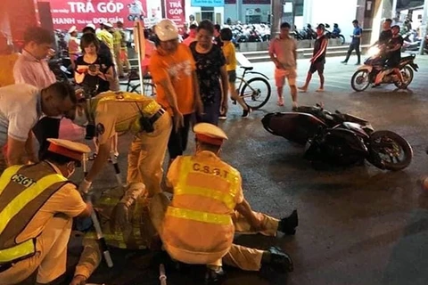 Đồng đội, nhân dân sơ cứu và đưa chiến sỹ công an bị hai đối tượng đâm xe. (Nguồn: cand.com.vn)