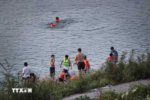 Người lớn lẫn trẻ em xuống tắm sông Đà trong những ngày nắng nóng, bất chấp những biển cảnh báo nguy hiểm được các đơn vị chức năng cắm trên bờ sông. (Ảnh: Trọng Đạt/TTXVN)