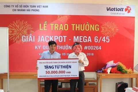 Anh Nguyễn Quốc Thịnh trao quà sau khi nhận giải Jackpot. (Ảnh: Vietlott)