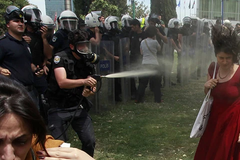 Cô gái mặc váy đỏ bị cảnh sát xịt hơi cay vào mặt. (Nguồn: Reuters)