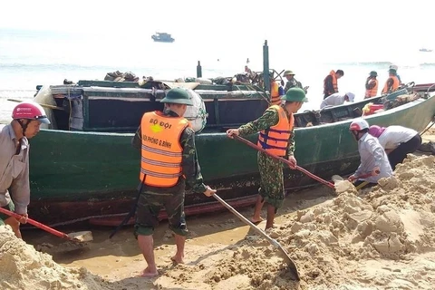 Cán bộ, chiến sĩ bộ đội biên phòng cùng nhân dân địa phương hỗ trợ giải cứu tàu cá gặp nạn. (Ảnh: Võ Dung/TTXVN)