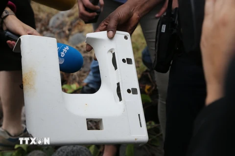 Cảnh sát Pháp với tấm nhựa vừa phát hiện trên đảo Reunion. (Nguồn: AFP/TTXVN)