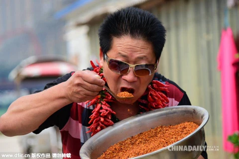 Ông Lý Vĩnh Chí biểu diễn khả năng ăn ớt đặc biệt của mình. (Nguồn: Chinadaily)
