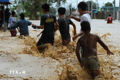 Người dân vượt qua vùng nước lũ do mưa bão ở khu dân cư thị trấn Santa Rosa, tỉnh Nueva Ecija, phía bắc thủ đô Manila ngày 19/10. (Nguồn: AFP/TTXVN)