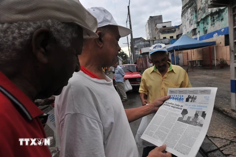 Người dân Cuba theo dõi thủ tục xuất cảnh mới trên báo Granma. (Nguồn: AFP/TTXVN)