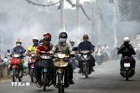 Người dân đi ngoài đường luôn phải bịt khẩu trang để tránh hít phải khói bụi. (Ảnh: Hoàng Hải/TTXVN)