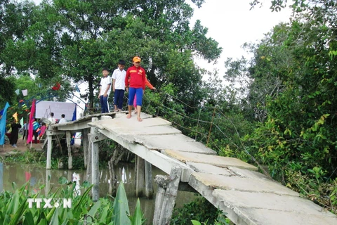 Tiềm ẩn tai nạn cho trẻ nhỏ khi đi qua cây cầu tạm tại xã Phước Chỉ, huyện Trảng Bảng. (Ảnh: Thanh Tân/TTXVN)