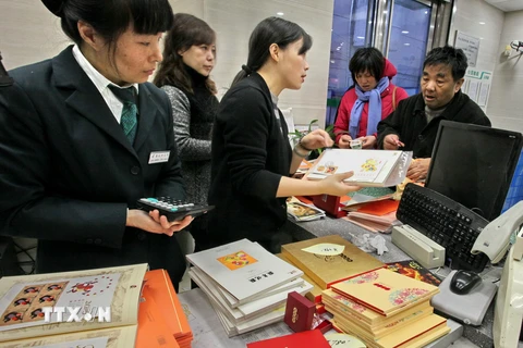 Người dân mua các mẫu tem trong bộ tem đặc biệt mừng Tết Bính Thân tại bưu điện ở Thượng Hải. (Nguồn: THX/TTXVN)