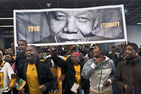 Người dân mang ảnh cố Tổng thống Nelson Mandela tới dự lễ tang tại Nam Phi. (Nguồn: AFP/TTXVN)