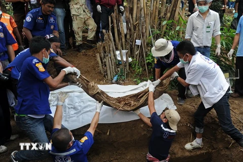 Lực lượng chức năng khai quật thi thể các nạn nhân trong ngôi mộ tập thể tại Thái Lan. (Nguồn: AFP/TTXVN)