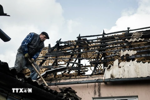Người dân địa phương sửa chữa căn nhà bị đổ nát trong xung đột tại Donetsk ngày 6/4. (Nguồn: AFP/TTXVN)