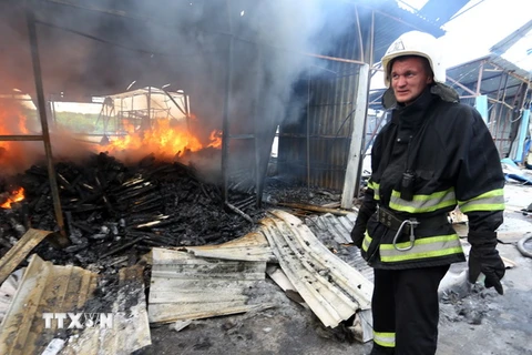 Lính cứu hỏa dập lửa đám cháy khu chợ ở Donetsk sau vụ pháo kích trong xung đột. (Nguồn: AFP/TTXVN)