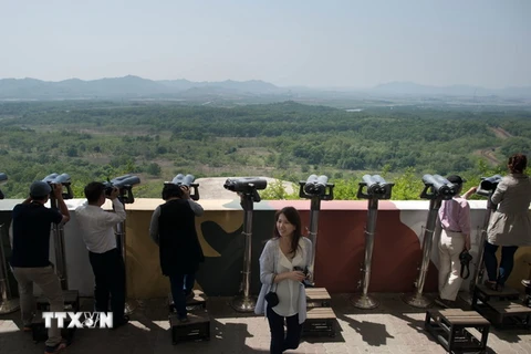 Khách du lịch ngắm phong cảnh qua đài quan sát gần khu phi quân sự Panmunjom giữa Hàn Quốc và Triều Tiên. (Nguồn: AFP/TTXVN)