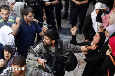 Cảnh sát Israel bắt giữ một phụ nữ Palestine trong cuộc xung đột giữa cảnh sát và người biểu tình tại thánh địa Jerusalem. (Nguồn: AFP/TTXVN)
