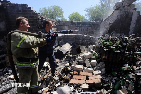 Lực lượng cứu hộ dập lửa đám cháy một nhà kho chứa lương thực bị trúng đạn pháo trong cuộc xung đột ở thị trấn Gorlivka, Donetsk ngày 3/8. (Nguồn: AFP/TTXVN)