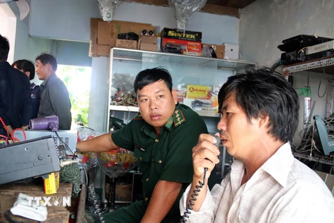 Người nhà anh Võ Văn Hưng theo dõi thông tin qua máy bộ đàm. (Ảnh : Đoàn Mạnh Dương/TTXVN)
