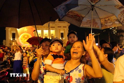 Người dân đứng tại Quảng trường Cánh mạng Tháng Tám xem bắn pháo hoa khu vực Hồ Hoàn Kiếm (Hà Nội). (Ảnh: Quý Trung/TTXVN)