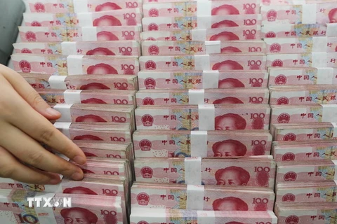 Kiểm tiền giấy mệnh giá 100 nhân dân tệ tại ngân hàng ở Liên vận cảng, tỉnh Giang Tô, Trung Quốc ngày 11/8. (Nguồn: AFP/TTXVN)