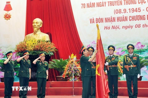 Thượng tướng Đỗ Bá Tỵ gắn Huân chương Bảo vệ Tổ quốc hạng Nhì lên Cờ truyền thống của Cục Quân lực. (Ảnh: Trọng Đức/TTXVN)