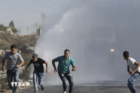 Người Palestine chạy trốn vòi rồng do cảnh sát Israel sử dụng trong xung đột tại Thánh đường al-Aqsa ở Jalazoun, gần thành phố Ramallah ngày 18/9. (Nguồn: Reuter/TTXVN)