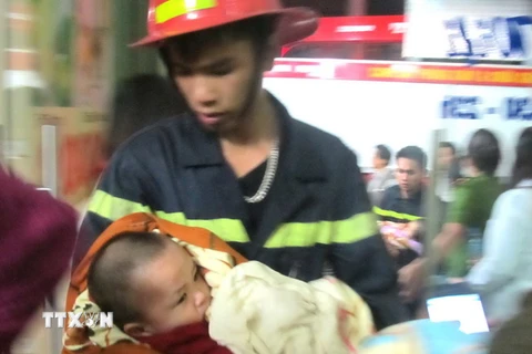 Cảnh sát chữa cháy cứu cháu bé khỏi nơi xảy ra cháy. (Ảnh: Doãn Tấn/TTXVN)