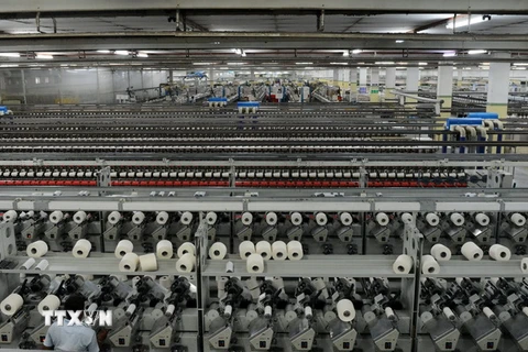 Công nhân làm việc tại nhà máy dệt ở làng Khatraj, cách Ahmedabad, bang Gujarat khoảng 20km ngày 8/7. (Nguồn: AFP/TTXVN)