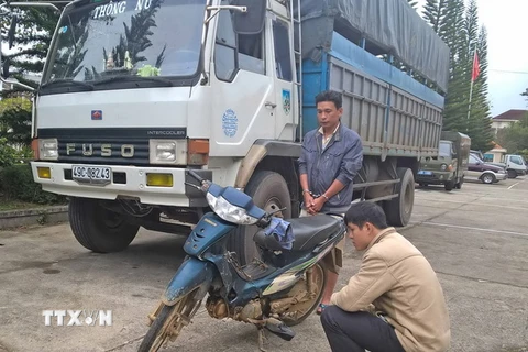 Tài xế Duy (áo xanh) cùng chiếc xe tải tại trụ sở Công an thành phố Đà Lạt. (Ảnh: Nguyễn Dũng/TTXVN)