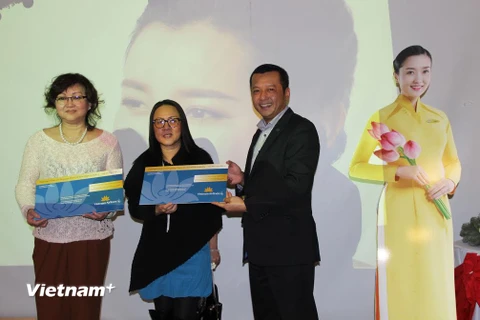 Ông Ngô Trí Hưng, Trưởng Chi nhánh Vietnam Ailines tại Đức, trao vé máy bay cho khách hàng may mắn trúng thưởng. (Ảnh: Mạnh Hùng/Vietnam+)