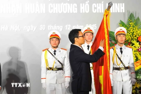 Phó Thủ tướng Vũ Đức Đam gắn Huân chương Hồ Chí Minh lên lá cờ truyền thống của Trường Đại học Mỹ thuật Việt Nam. (Ảnh: Minh Đức/TTXVN)