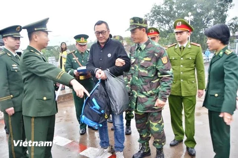 Công an Quảng Ninh trao trả đối tượng bị truy nã Quách Lâm (người đeo kính, mặc áo khoác đen) cho công an Trung Quốc. (Ảnh: Văn Đức/Vietnam+)