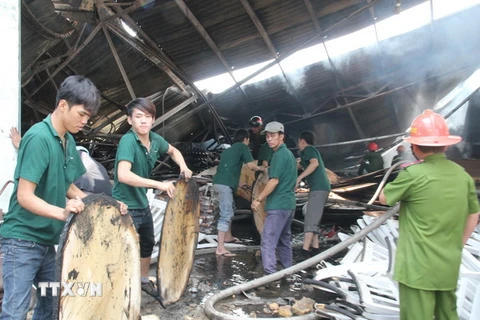 Công nhân và bảo vệ công ty Wang Feng đang khẩn trương sơ tán tài sản ra khỏi đám cháy. (Ảnh: Dương Chí Tưởng/TTXVN)