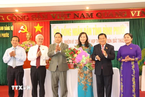 Huỳnh Thị Hằng (đứng giữa) nhận hoa chúc mừng của lãnh đạo tỉnh Bình Phước. (Ảnh: Nguyễn Văn Việt/TTXVN)