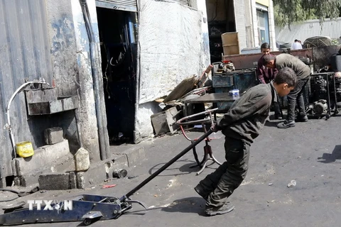 Một cậu bé Syria 12 tuổi phải làm các công việc nặng nhọc để kiếm sống tại một xưởng cơ khí ở thủ đô Damascus ngày 10/3. (Nguồn: AFP/TTXVN)