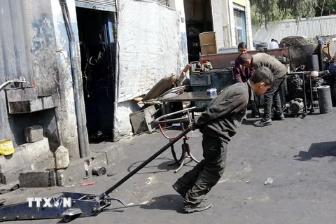 Một cậu bé Syria 12 tuổi phải làm các công việc nặng nhọc để kiếm sống tại một xưởng cơ khí ở thủ đô Damascus ngày 10/3. (Nguồn: AFP/TTXVN)