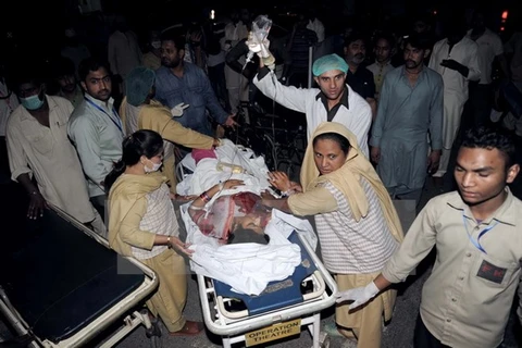 Chuyển người bị thương khỏi hiện trường vụ nổ bom. (Ảnh: AFP/ TTXVN)