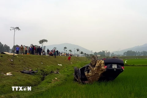 Chiếc xe ôtô hư hỏng nặng và nằm ngửa dưới ruộng lúa sau vụ tai nạn. (Ảnh: Tá Chuyên/TTXVN)