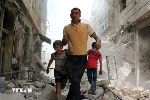 Người dân Syria sơ tán khỏi khu vực đổ nát sau một cuộc không kích ở Aleppo ngày 22/4. (Nguồn: AFP/TTXVN)