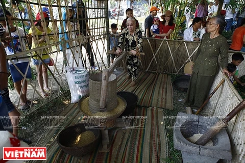 Người dân làng Thanh Toàn giới thiệu kỹ thuật xay lúa truyền thống tại phiên chợ qu. (Ảnh: Thanh Giang/Báo ảnh Việt Nam)