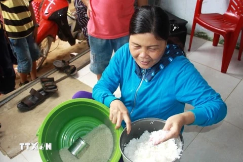 Bà Trương Thị Bé Đoan, khu dân cư số 7, cầm số gạo nghi trộn nhựa. (Ảnh: Vĩnh Trọng/TTXVN)