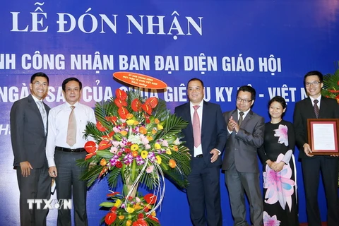 Phó Chủ tịch Ủy ban Trung ương Mặt trận Tổ quốc Việt Nam Lê Bá Trình (áo trắng, bên trái) tặng hoa chúc mừng Ban đại diện Giáo hội tại buổi lễ. (Ảnh: Nguyễn Dân/TTXVN)