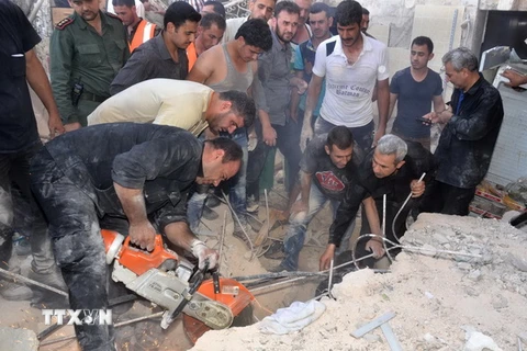 Lực lượng cứu trợ Syria tìm kiếm người sống sót trong đống đổ nát sau vụ pháo kích vào quận Hamdaniyeh, thành phố Allepo ngày 4/6. (Nguồn: AFP/TTXVN)