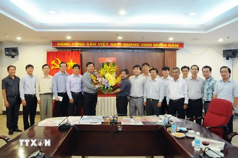 Bí thư Thành ủy TP. Hồ Chí Minh Đinh La Thăng tặng hoa chúc mừng các cán bộ, phóng viên cơ quan TTXVN khu vực phía Nam. (Ảnh: An Hiếu/TTXVN)