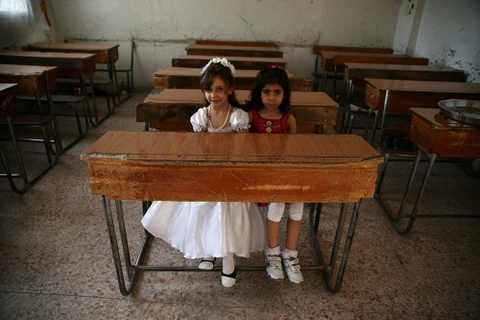 Những cô bé Syria xinh đẹp như búp bê trong một phòng học trống tại lễ bế giảng trong thị trấn Douma, Đông Ghouta, Syria ngày 21/5. (Nguồn: Sputnik)