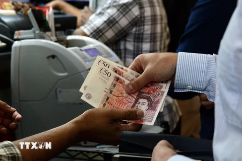 Kiểm đồng bảng Anh tại một điểm giao dịch ngoại hối ở Singapore ngày 24/6. (Nguồn: AFP/TTXVN)