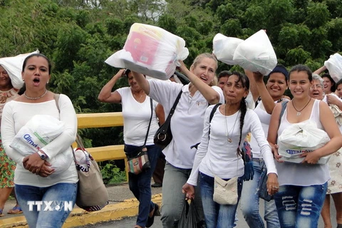 Người dân Venezuela vượt hàng rào chắn do quân đội dựng lên và tràn sang thành phố Cucuta, Colombia để mua lương thực, thực phẩm và thuốc men ngày 5/7. (Nguồn: EPA/TTXVN)