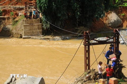 Hàng tiếp tế được vận chuyển bằng cáp treo qua chiếc cầu đã bị sập đến hai thôn Sủng Hoảng 1, Sủng Hoảng 2. (Ảnh: Hương Thu/TTXVN)