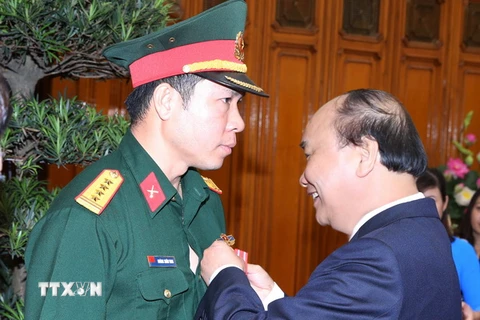 Thủ tướng Nguyễn Xuân Phúc trao tặng Huân chương lao động hạng Nhất cho vận động viên Hoàng Xuân Vinh. (Ảnh: Thống Nhất/TTXVN)