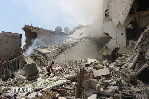 Nhân viên cứu hộ Syria tìm kiếm nạn nhân dưới những đống đổ nát sau vụ không kích tại Aleppo ngày 27/8. (Nguồn: AFP/TTXVN)