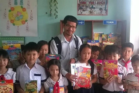 Ông Nguyễn Quang Thạch và các em nhỏ bên những cuốn sách từ chương trình "Sách hóa nông thôn." (Nguồn: Vietnam+)